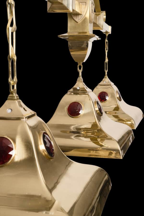 Three golden pendant lights with red gem-like embellishments against a black background.
