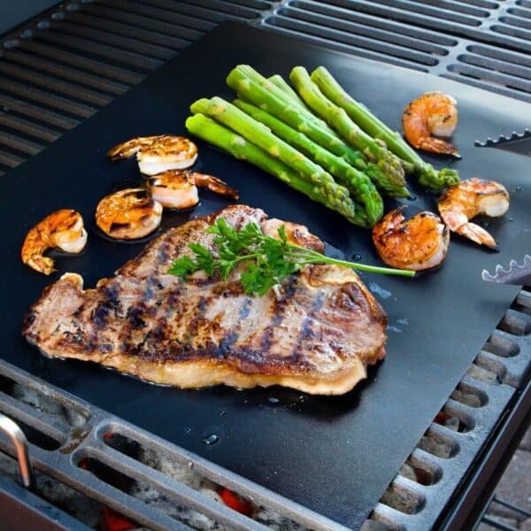 A grill with steak, asparagus and shrimp on it.