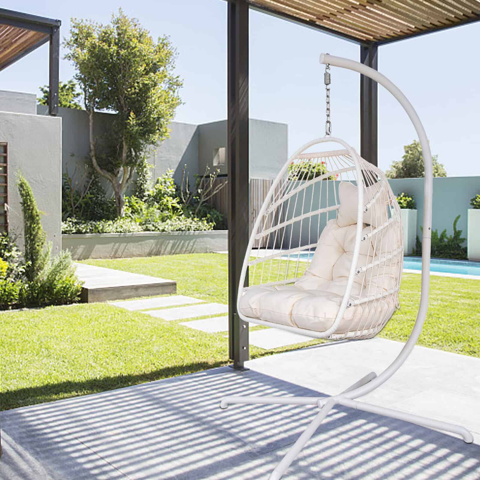 A white hanging chair in a backyard with a pool.