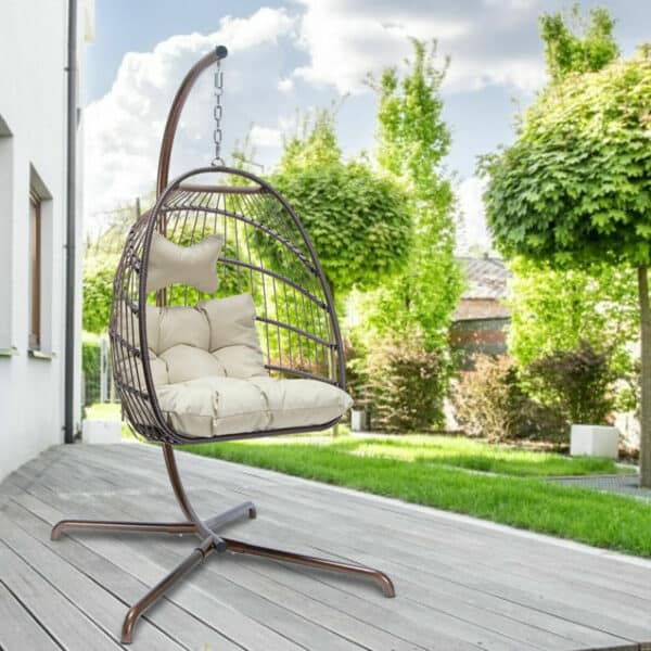 A rattan swing chair on a wooden deck.