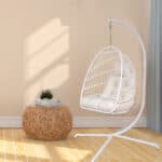 A white rattan hanging chair in a room.