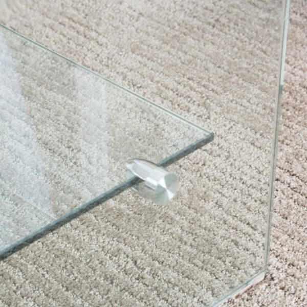 A close up of a glass coffee table on a carpet.