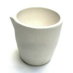 White ceramic cup with broken edge on a white background.