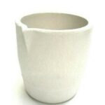 A white, broken ceramic mug with a missing handle.