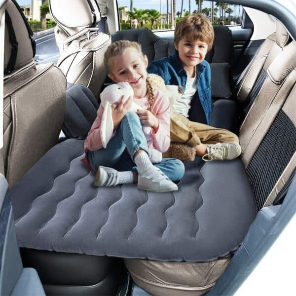 Two children smiling in the back seat of a car with an inflatable seat cushion.