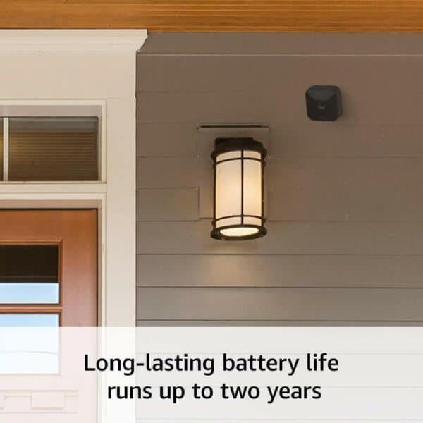 A smart home security camera mounted beside an outdoor light fixture with a caption highlighting its long-lasting battery life.