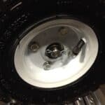 Close-up view of a vehicle's wheel mounted on a white rim, featuring a fresh tire with studs for improved traction.