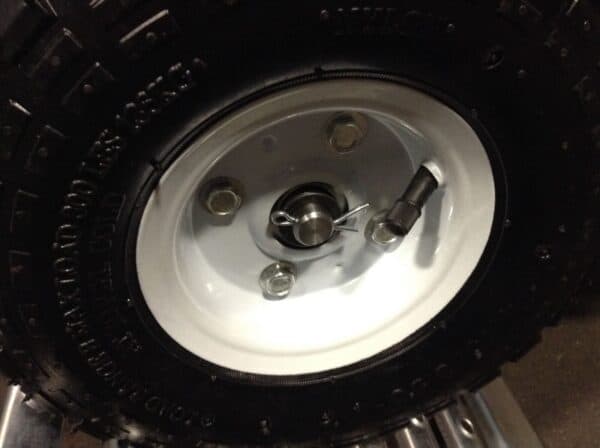 Close-up view of a vehicle's wheel mounted on a white rim, featuring a fresh tire with studs for improved traction.