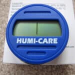 A blue humi-care humidity indicator card placed on top of its packaging.