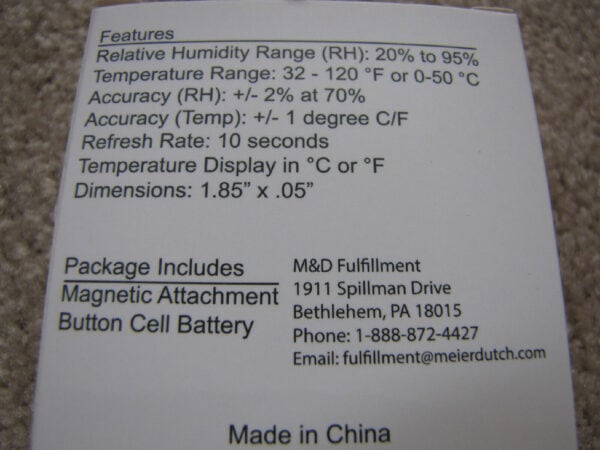 Close-up of a product information label detailing specifications like temperature range, humidity range, accuracy, refresh rate, and dimensions, as well as package contents and customer support contact information.