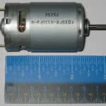 Small electric motor placed next to a ruler for size comparison.