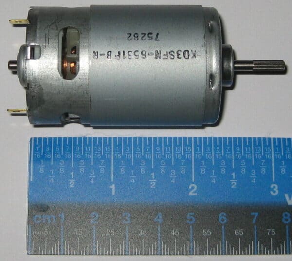 Small electric motor placed next to a ruler for size comparison.