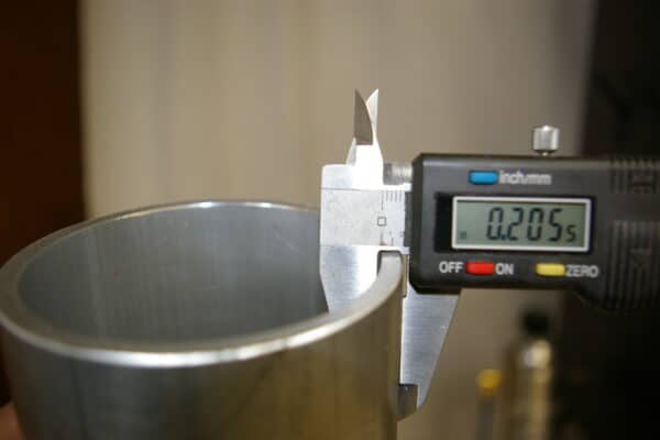 Digital calipers measuring the thickness of a metallic object.