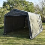 Portable garage tent set up on grass.