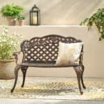 An outdoor bench with a yellow rug and potted plants.