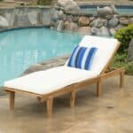 A wooden chaise lounge next to a pool.