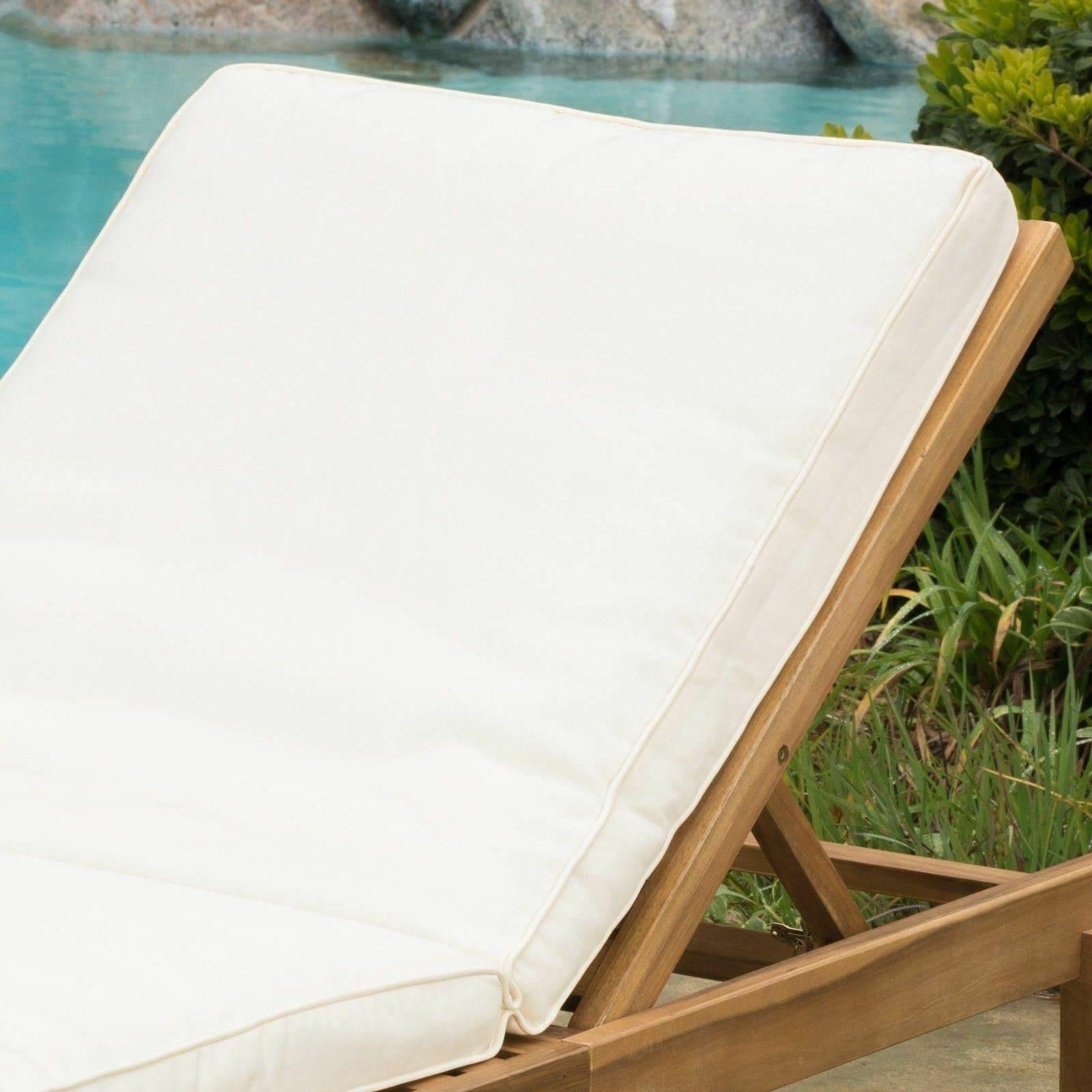 A white chaise lounge next to a pool.