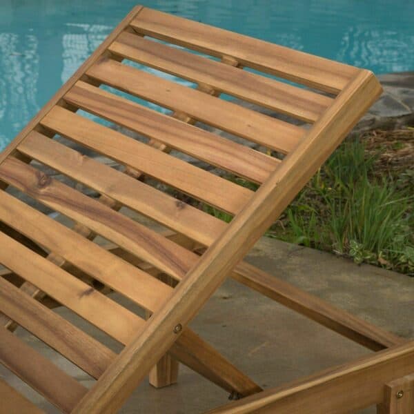 A wooden chaise lounge next to a pool.