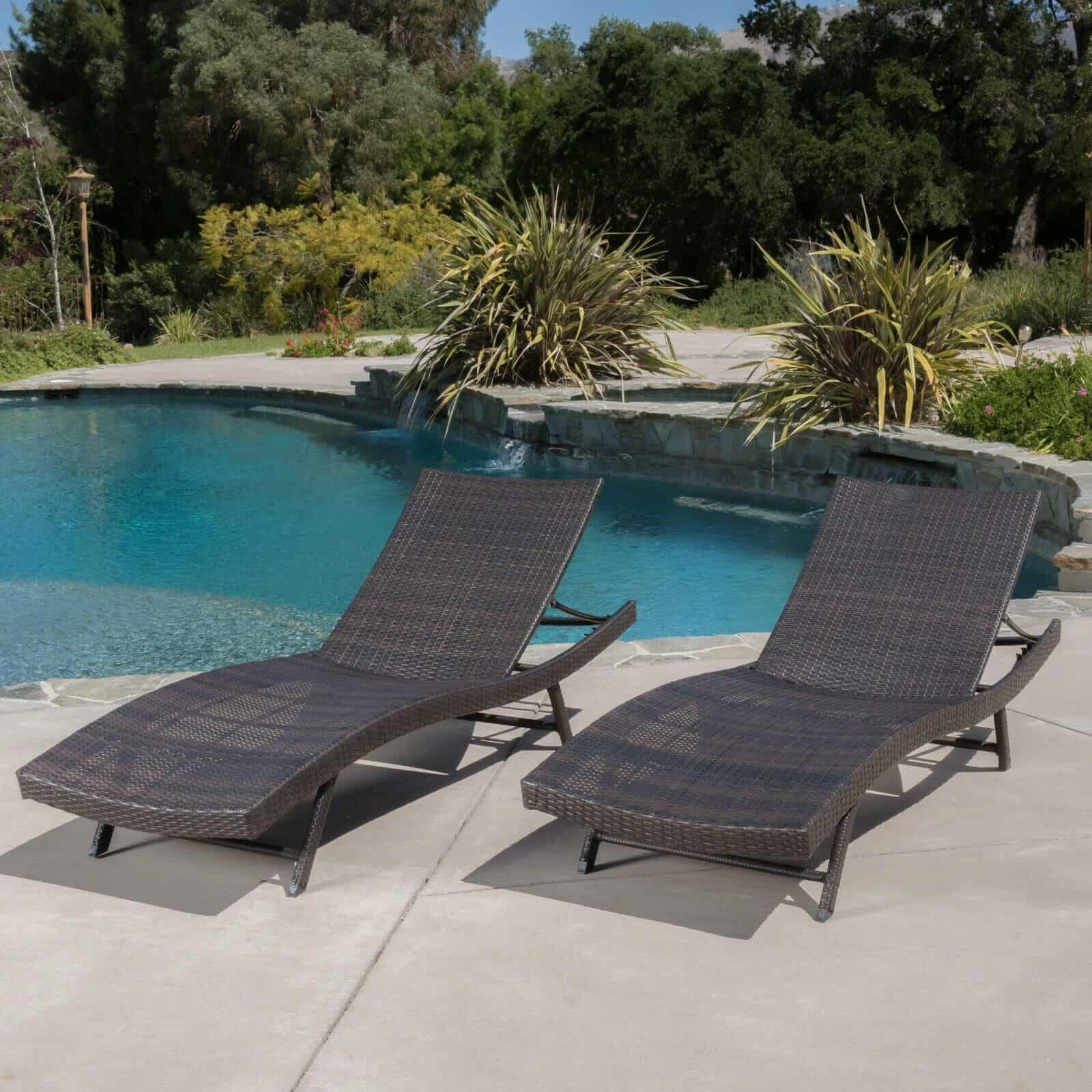Two chaise loungers in front of a pool.