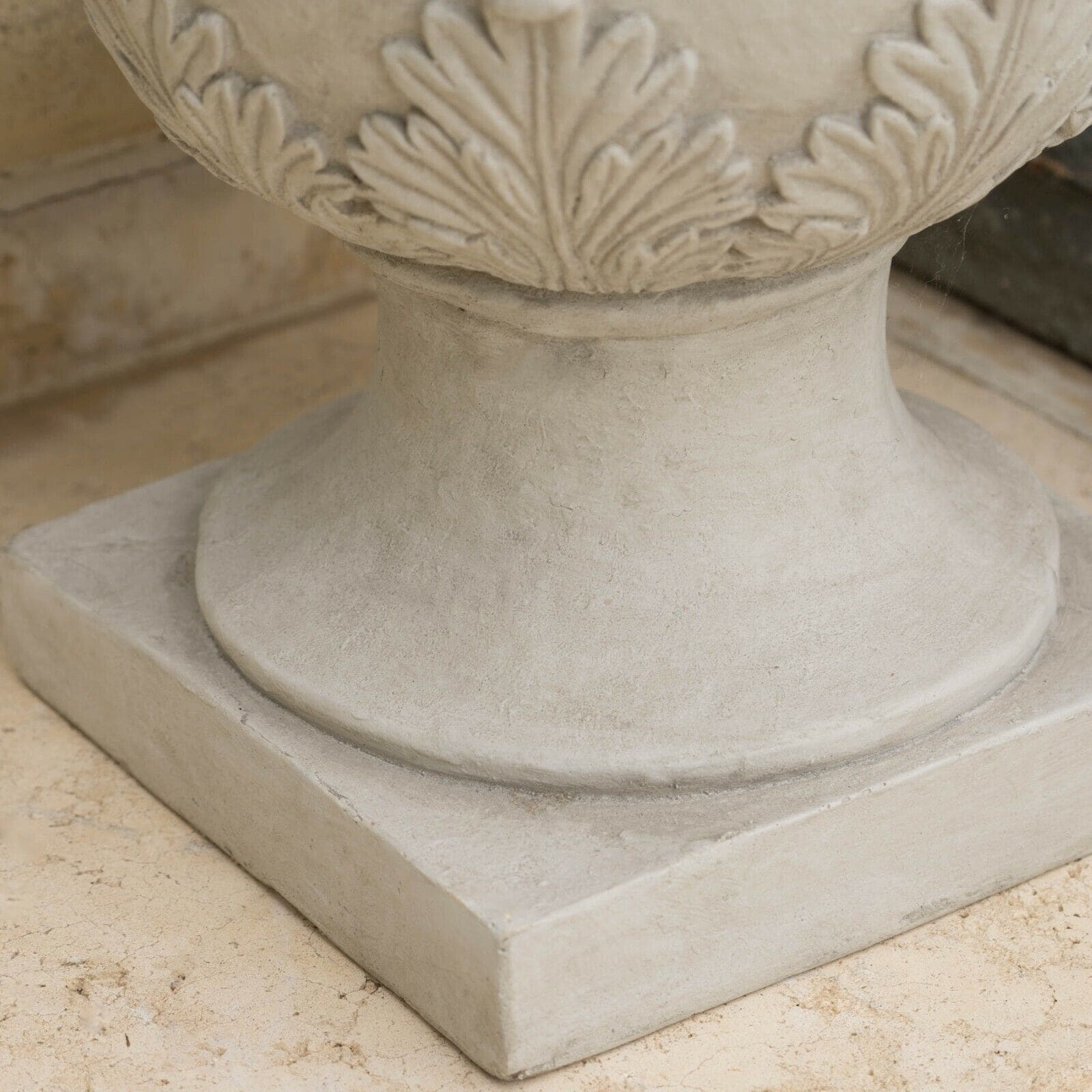 A white urn on top of a tiled floor.