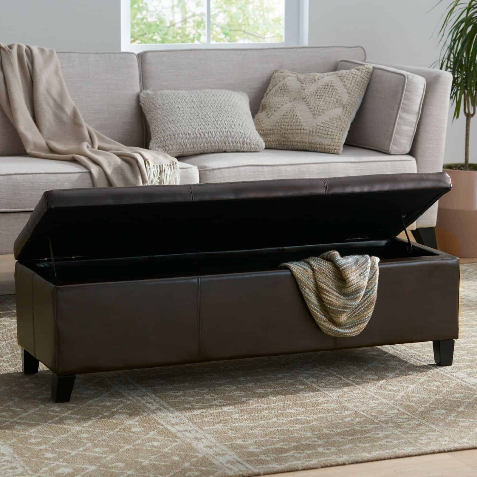 A brown leather storage bench in a living room.