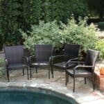 Four wicker chairs next to a pool.