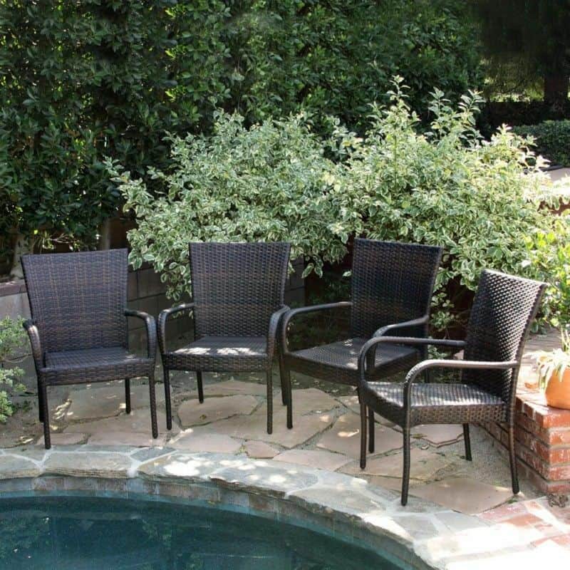 Four wicker chairs next to a pool.