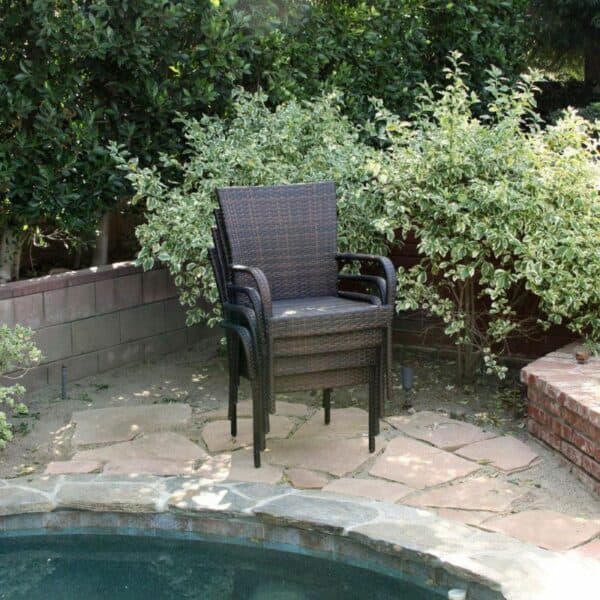 A wicker chair next to a pool in a backyard.