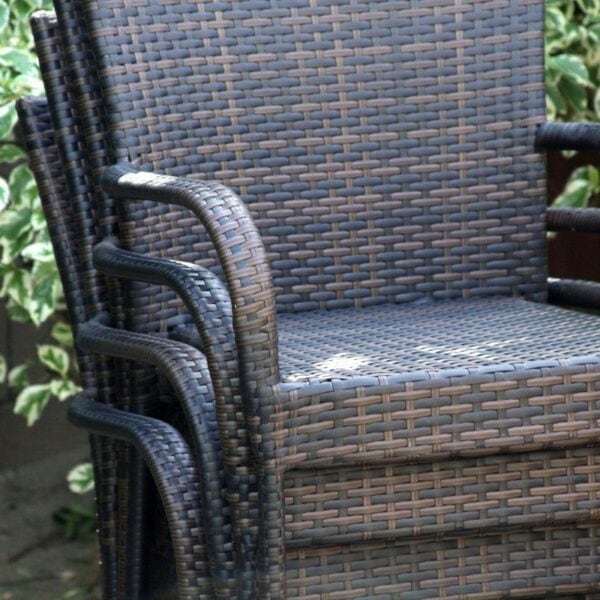 A set of wicker chairs in front of bushes.