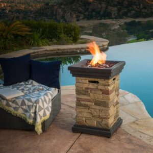 A fire pit on a patio next to a pool.