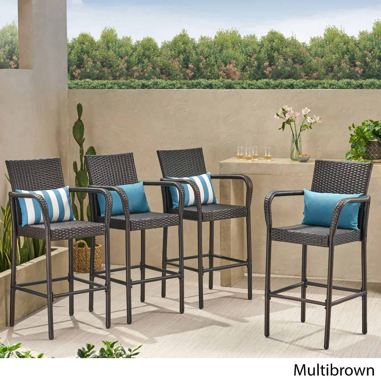 Four outdoor wicker bar stools with blue cushions.