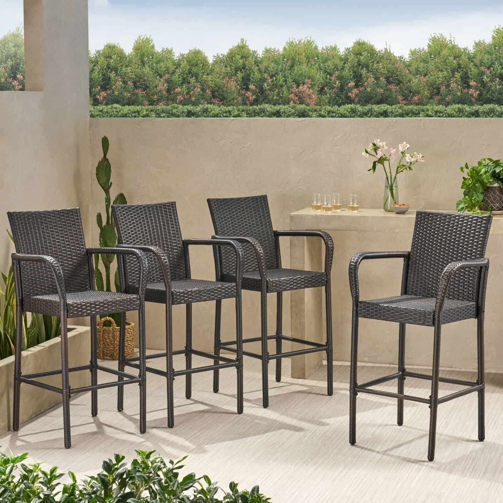 Four wicker bar stools on a patio.