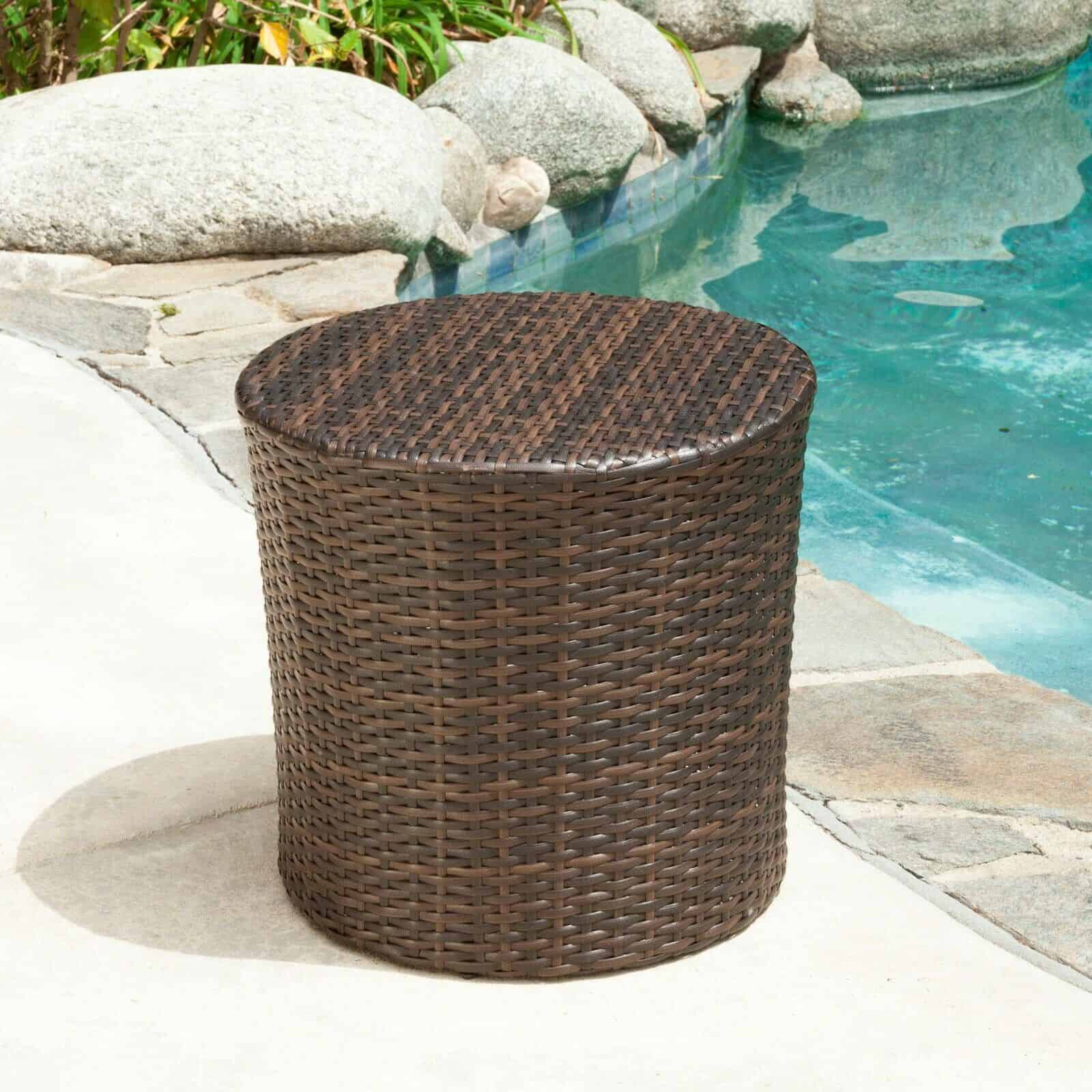 A wicker side table next to a pool.