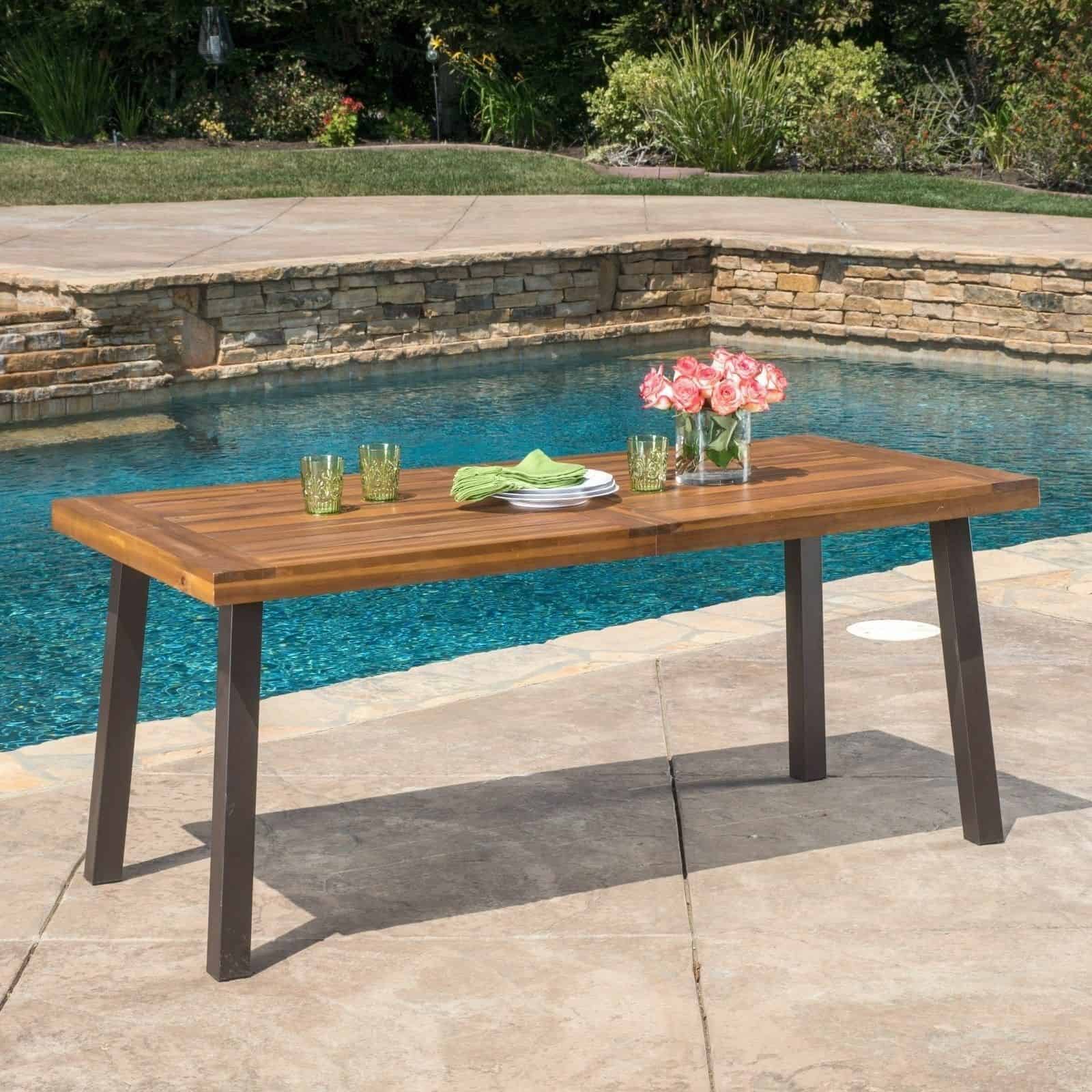 An outdoor dining table next to a pool.