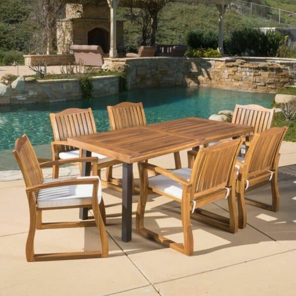 A teak dining set with six chairs and a pool.