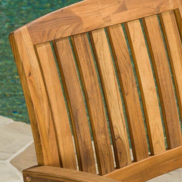 A wooden chair in front of a swimming pool.