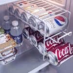 A refrigerator with several cans of soda in it.