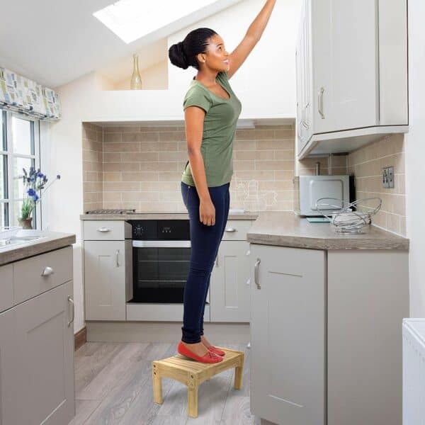 A woman standing on a stool in a kitchen.