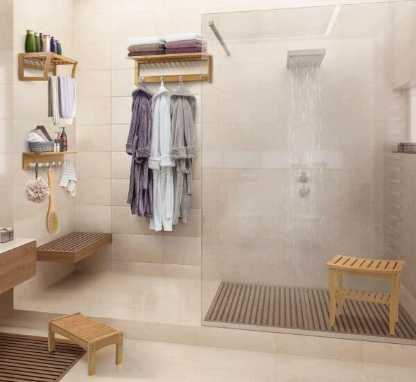 A bathroom with a glass shower stall and a wooden bench.