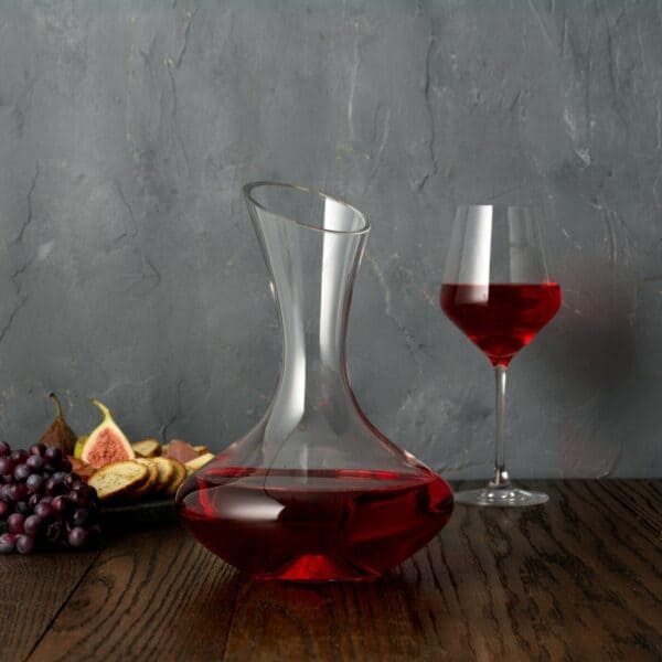 A red wine decanter next to a glass of red wine.