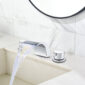 A bathroom sink with a waterfall faucet and mirror.