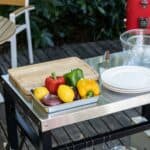 A kitchen cart with plates and vegetables on it.