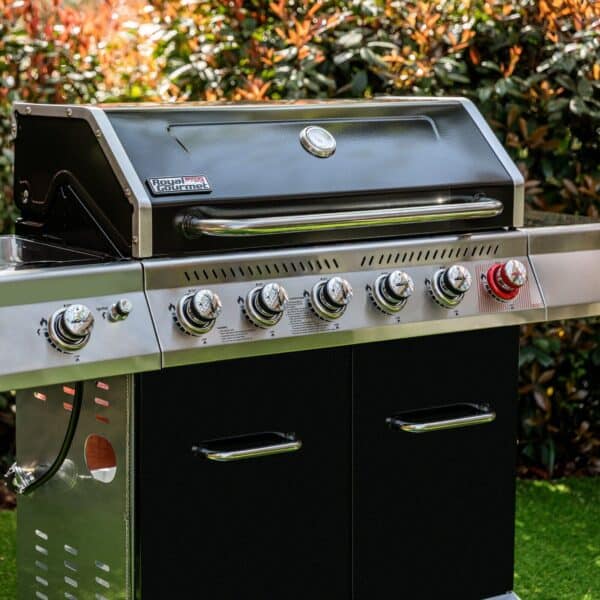 A black grill with four burners in the grass.