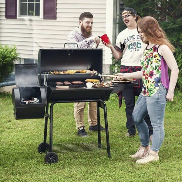 A group of people standing around a bbq grill.