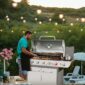 A man is preparing food on a gas grill.