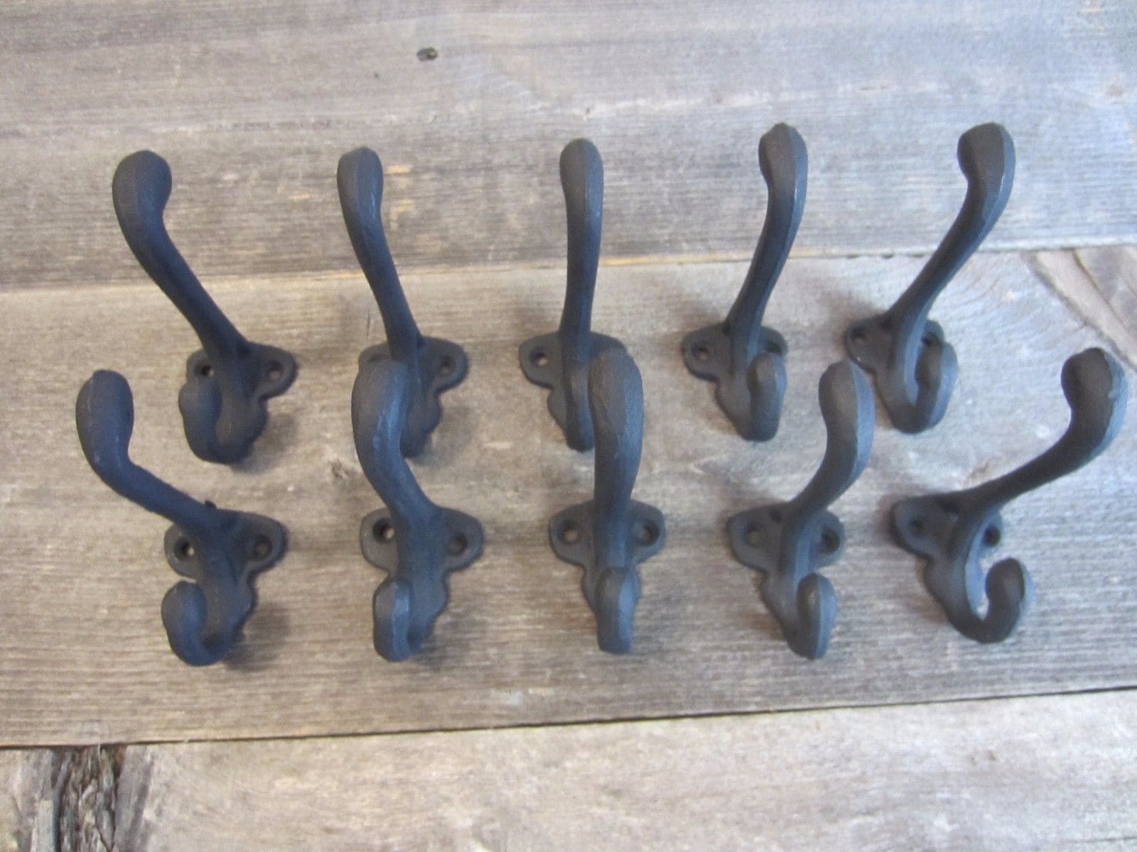A row of black iron hooks on a wooden surface.