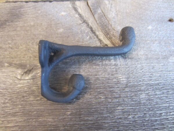 A black iron hook on a wooden surface.