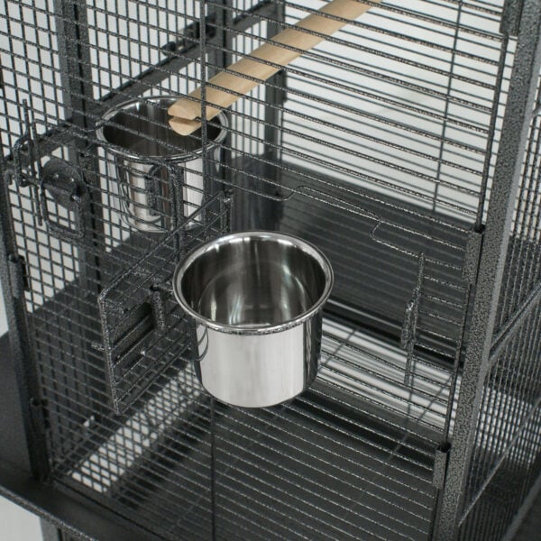 A bird cage with two cups and a bowl.
