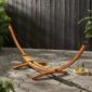 A wooden hammock on a concrete patio.