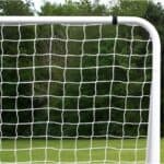 A soccer goal with a net in the middle of a field.